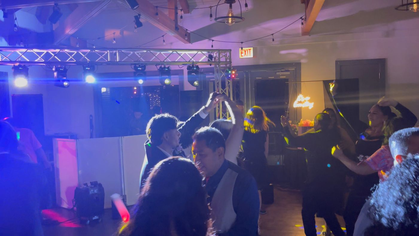 Luces móviles sobre una estructura de truss mientras los invitados bailan en una boda