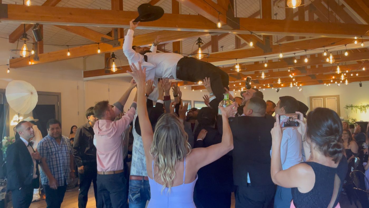 Invitados levantando al novio en el aire durante la fiesta