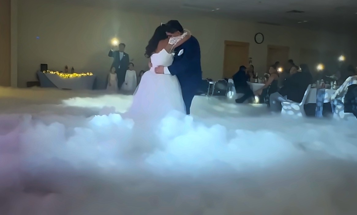 Novios abrazados en su primer baile sobre una capa de niebla baja