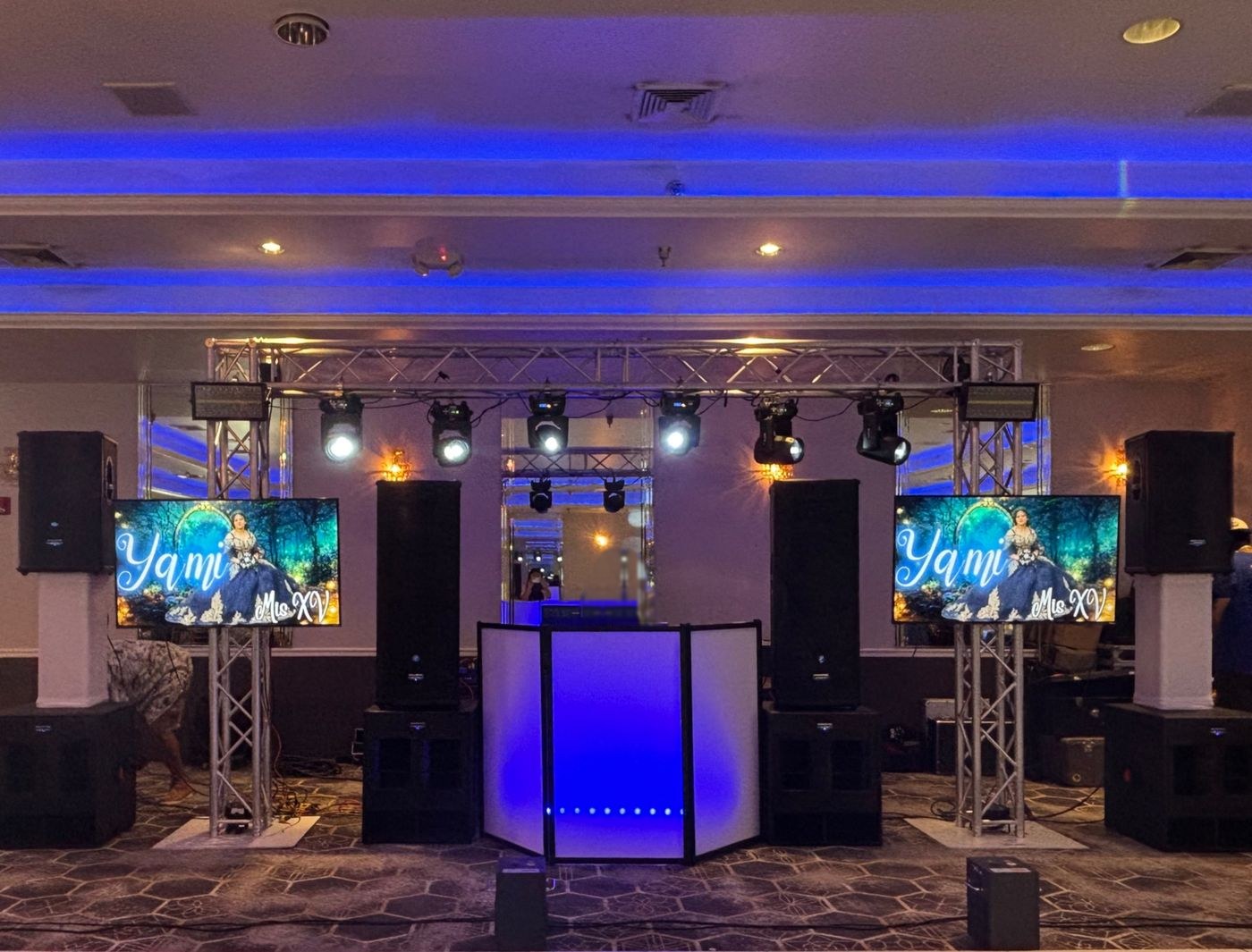 Cabina del DJ con dos pantallas HD que muestran el nombre de la quinceañera, bocinas y luces móviles en truss