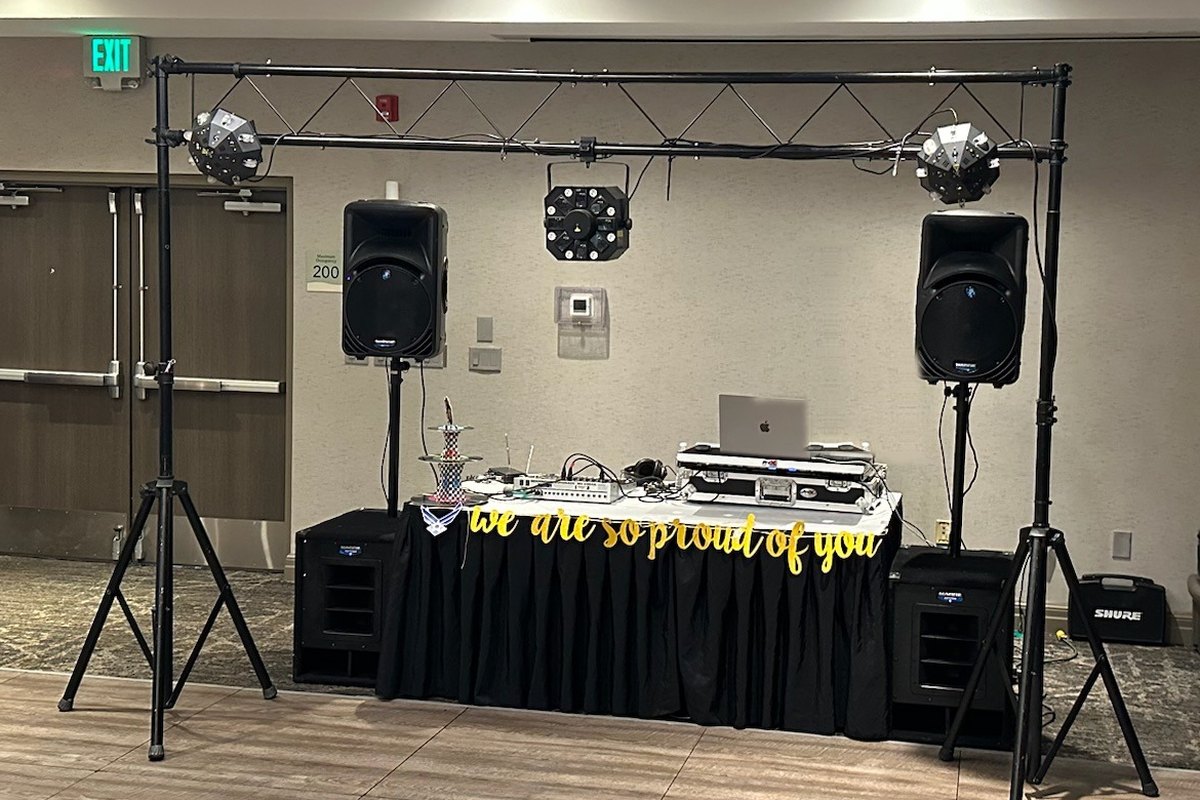 Montaje Esencial: DJ con dos bocinas en pedestal, subwoofers, truss con luces inteligentes y mesa con falda negra